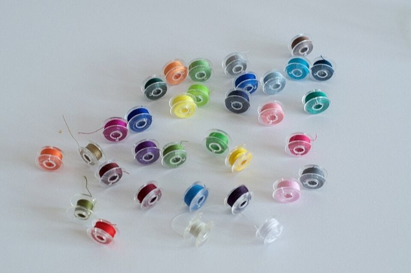 Canillas de plástico transparente bobinadas con hilo de distintos colores