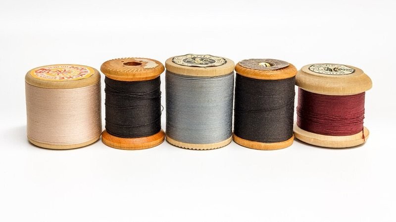 Cinco carretes de hilo de coser de madera en distintos colores