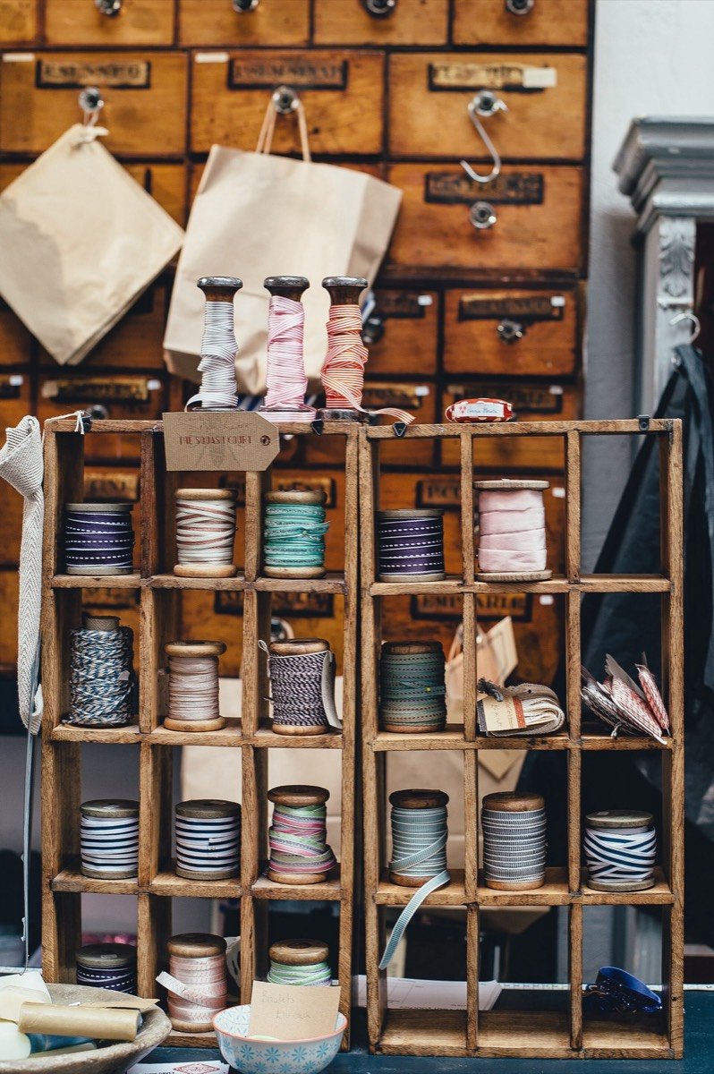 Estantes de madera con carretes de cinta y cordel de colores en una mercería