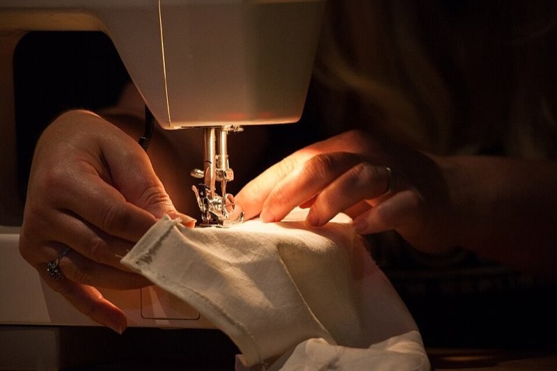 Manos cosiendo una tela con una máquina de coser doméstica Singer