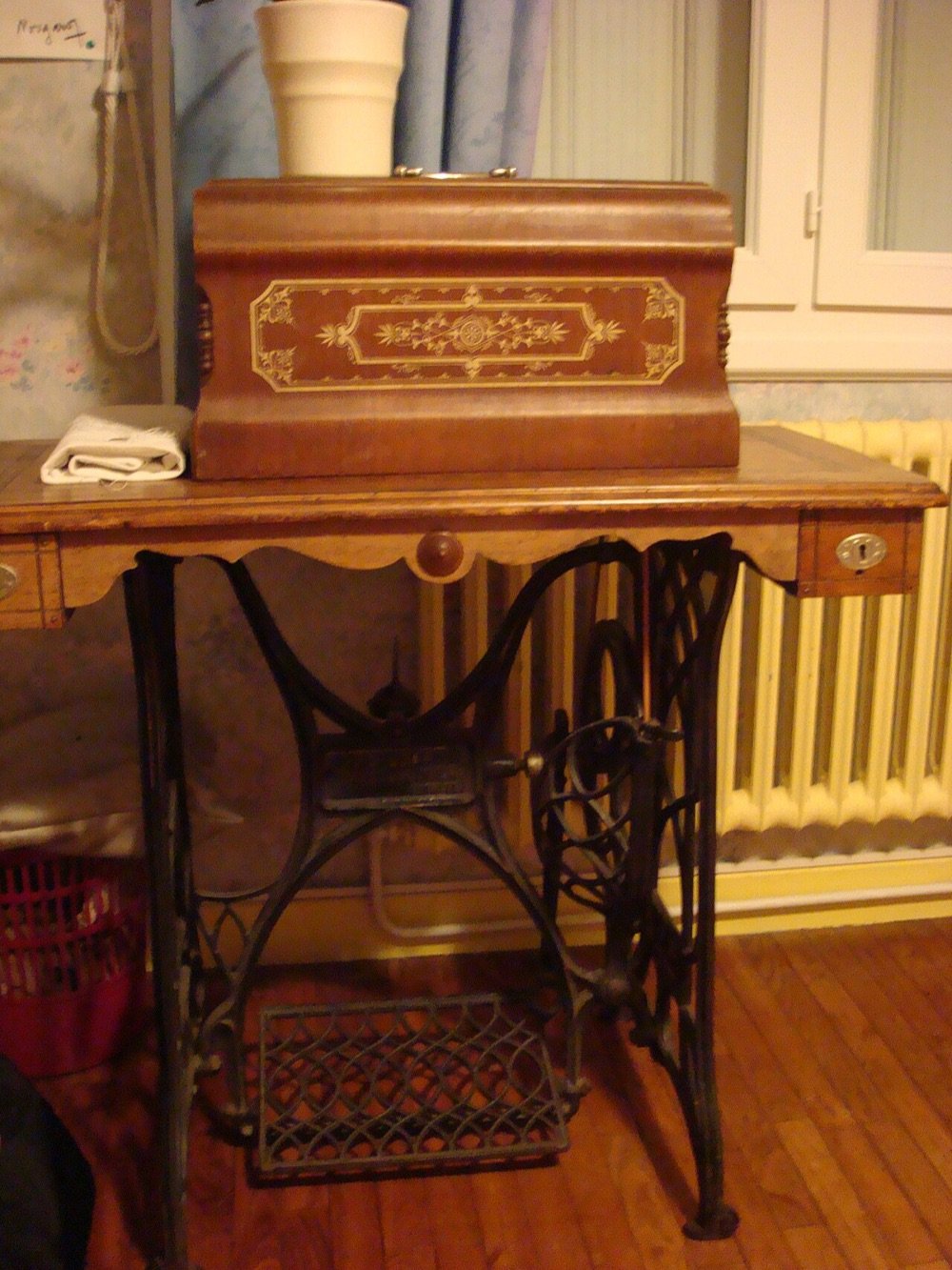 Máquina de coser antigua con mueble de madera y pedal de hierro forjado